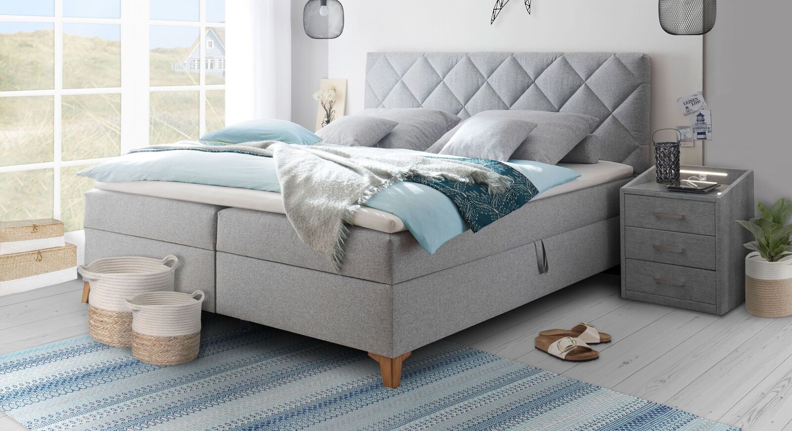 Nordische Gemütlichkeit: das silbergraue Bettkasten-Boxbett "Bolton" im lässigen Scandi Style mit gestepptem Polster-Kopfteil.