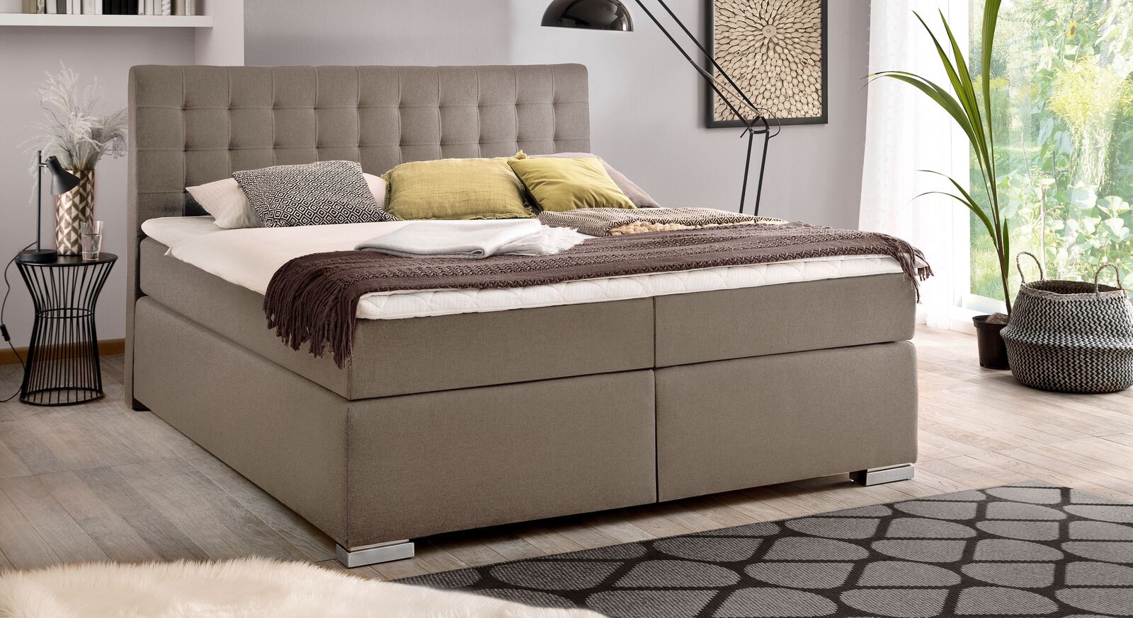 Der feine taupefarbene Webstoff unterstreicht das klassische Design des Bettkasten-Boxspringbettes "Santera" (hier mit Metallfüßen).