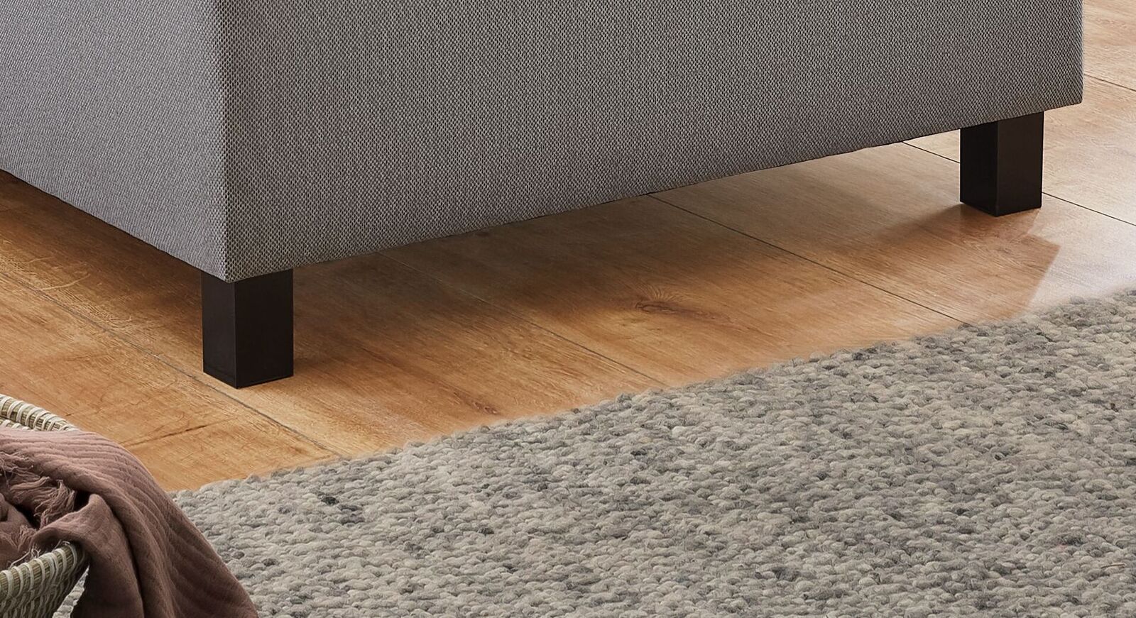 Getragen wird das Boxspring-Einzelbett von stabilen Bettbeinen aus schwarzem Kunststoff.