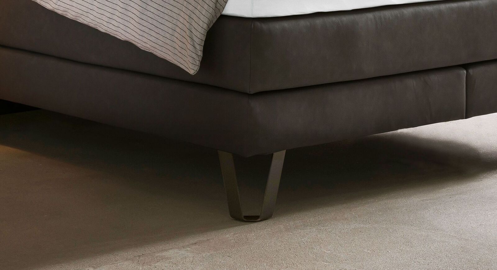 Die gebogenen Metallbeine passen perfekt zu dem Industrial Look des Boxspringbettes.