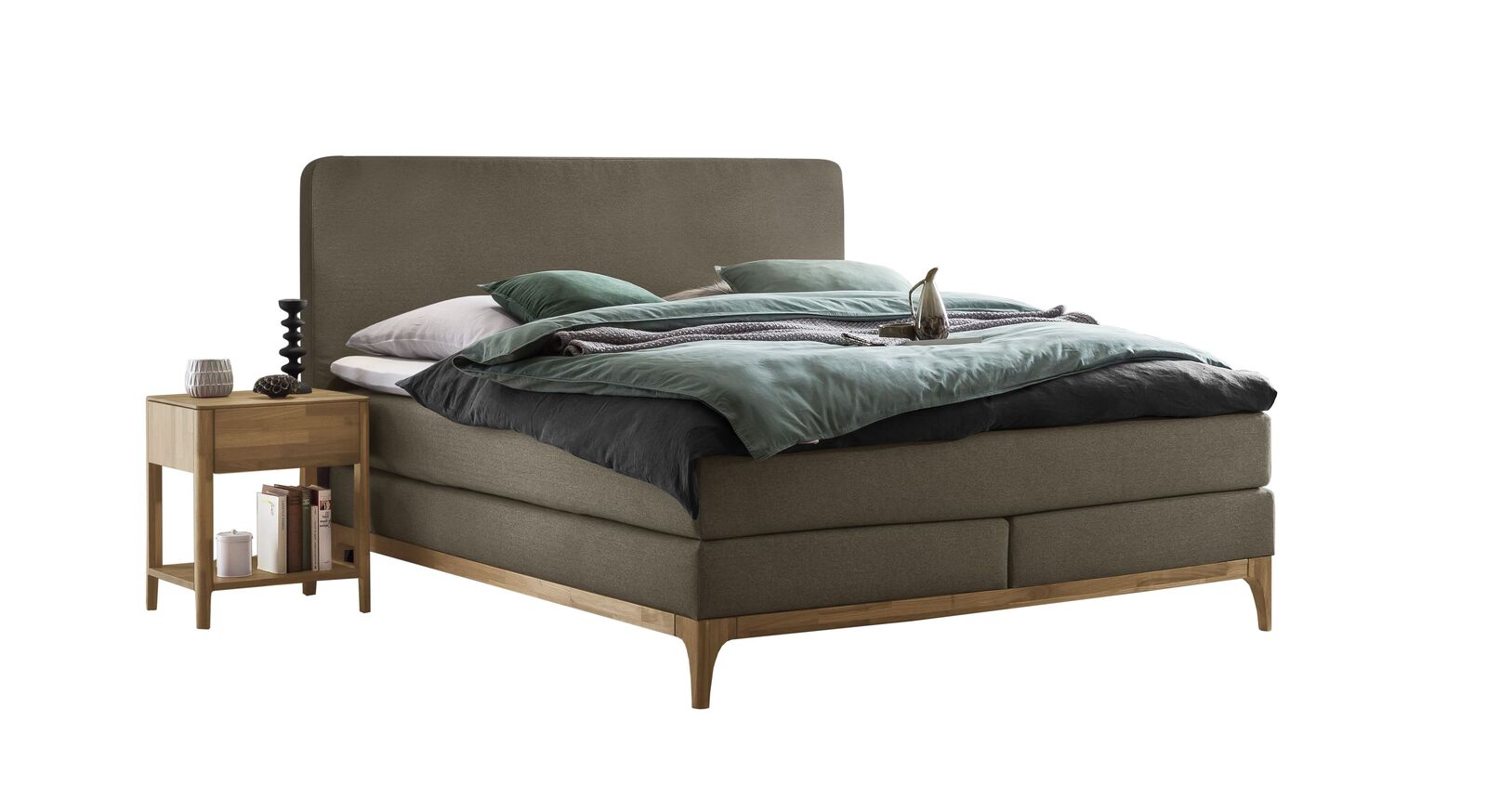 In der Farbe Sandgrau harmonieren der Bezug des Boxspringbettes "Conrado" und der Sockel aus Eichenholz bestens miteinander.