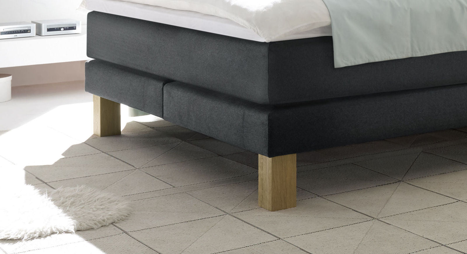 Elegante Blockfüße aus massiver, hell geölter Eiche sorgen für einen sicheren Stand des Boxspringbettes.