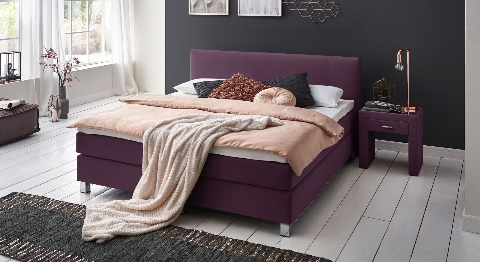 Ein Blickfang in jedem Schlafzimmer: das Boxspringbett "Ferryland" mit 53 cm Höhe und Bezug in Beere.