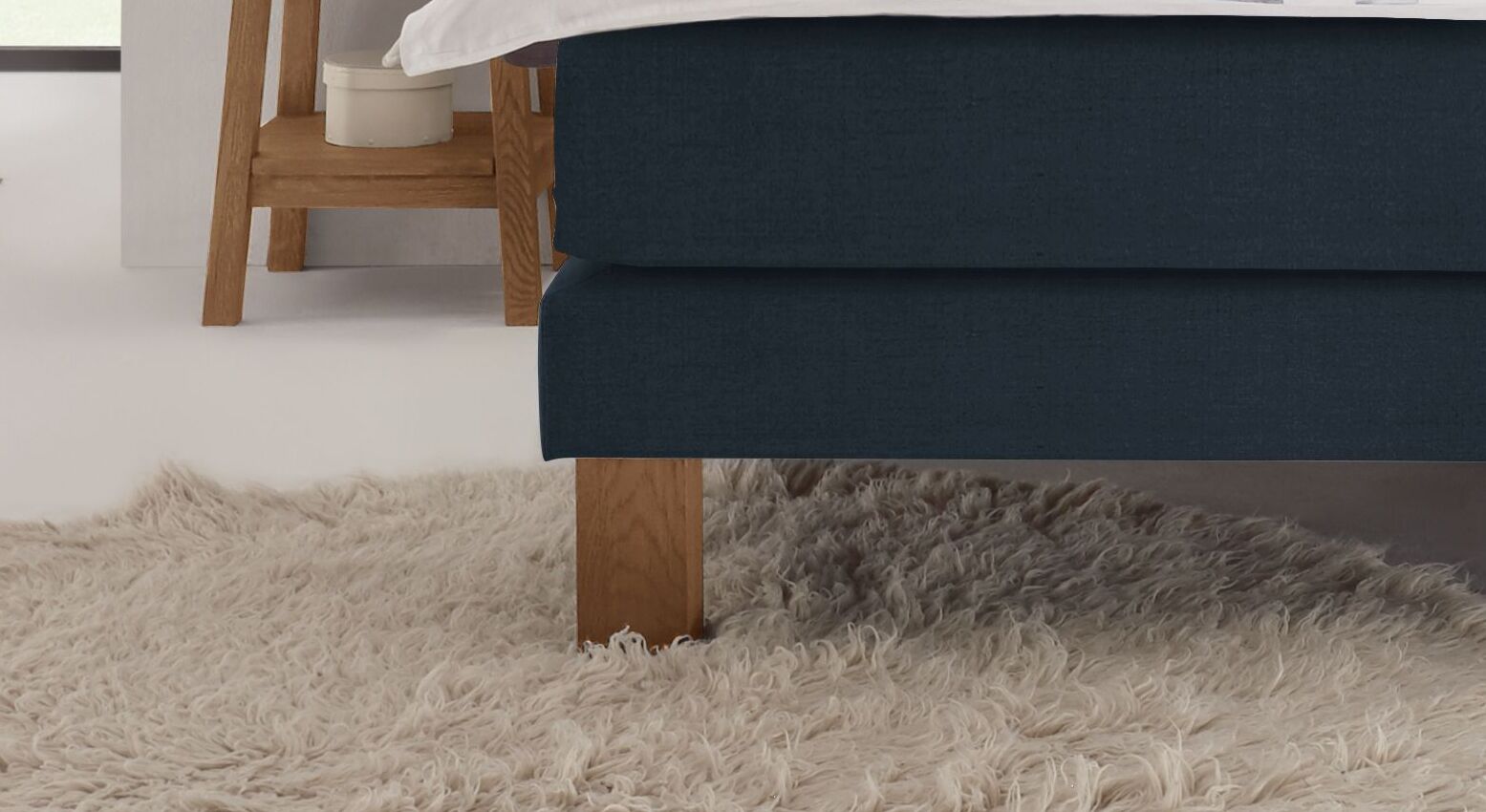 Für einen perfekten Stand ist das Boxspringbett "Oss" mit naturfarbenen Füßen aus Wildeiche ausgestattet.