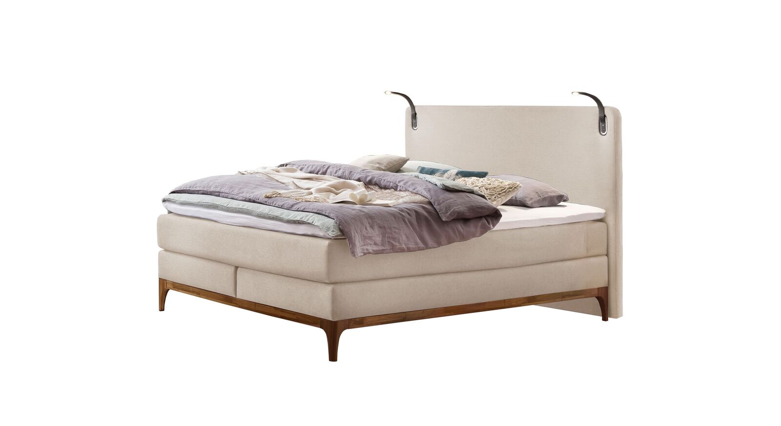 Kontrastreich: das Boxspringbett "Palmiro" in hellem Beige und dunklem Untergestell aus geöltem Nussbaumholz.