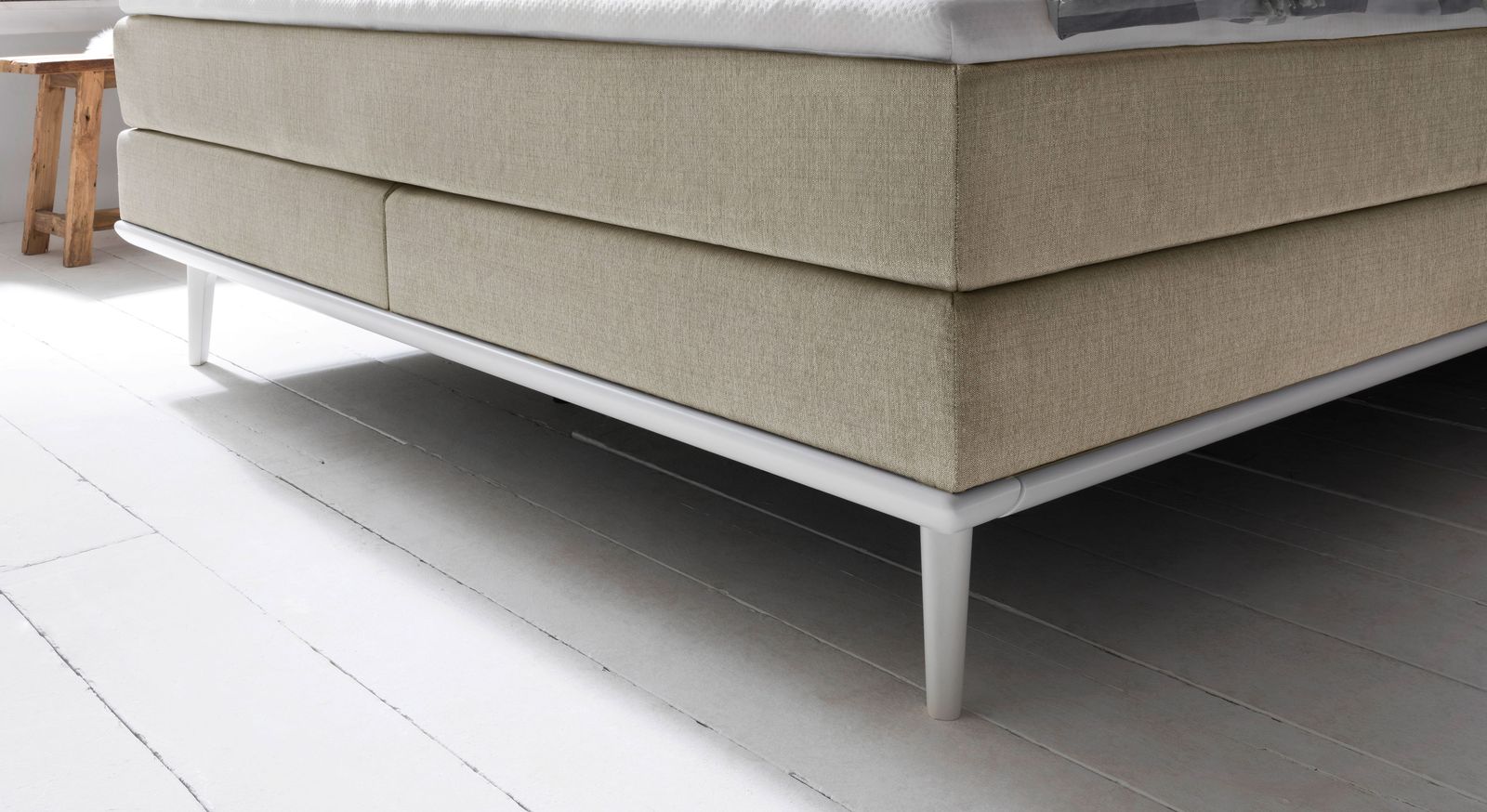 Optional ist das mittelweiche Boxspringbett "Paroldo" auch mit Massivholz-Unterleisten im Farbton der Füße lieferbar.