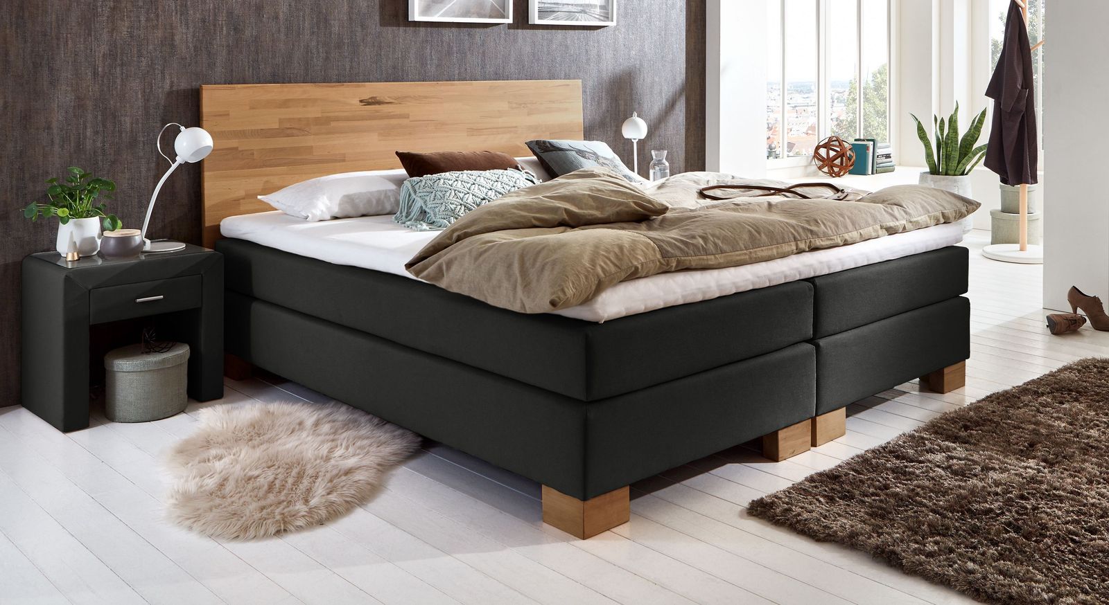 Gegensätze ziehen sich an: das niedrige Bett mit Kopfteil aus Holz und Gewand aus schwarzem Webstoff.