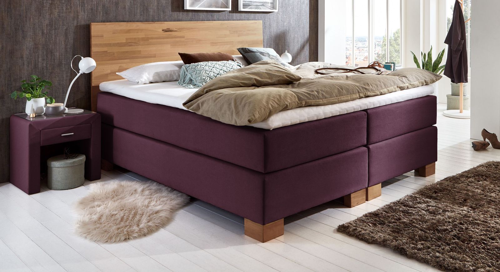 Perfekt für ein modernes Ambiente: das Bett (hohe Ausführung) mit einem Bezug im Farbton Beere.