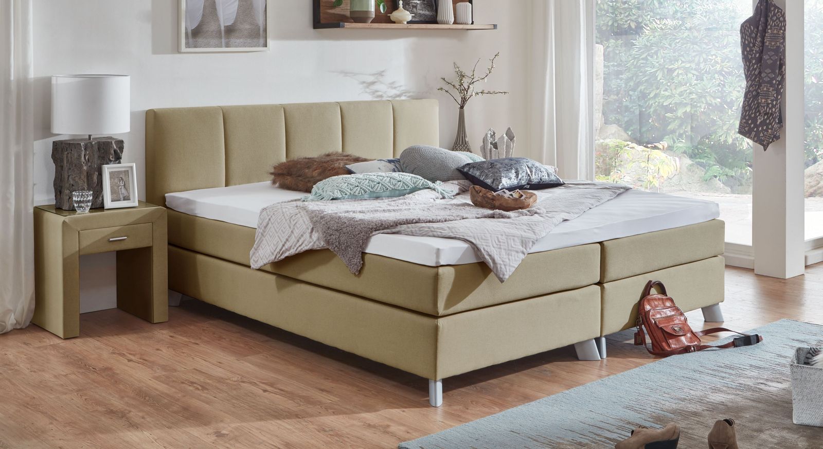 Das 53 cm hohe Boxspringbett "Ramea" ist hier mit einem robusten Webstoff in der Farbe Natur bezogen.
