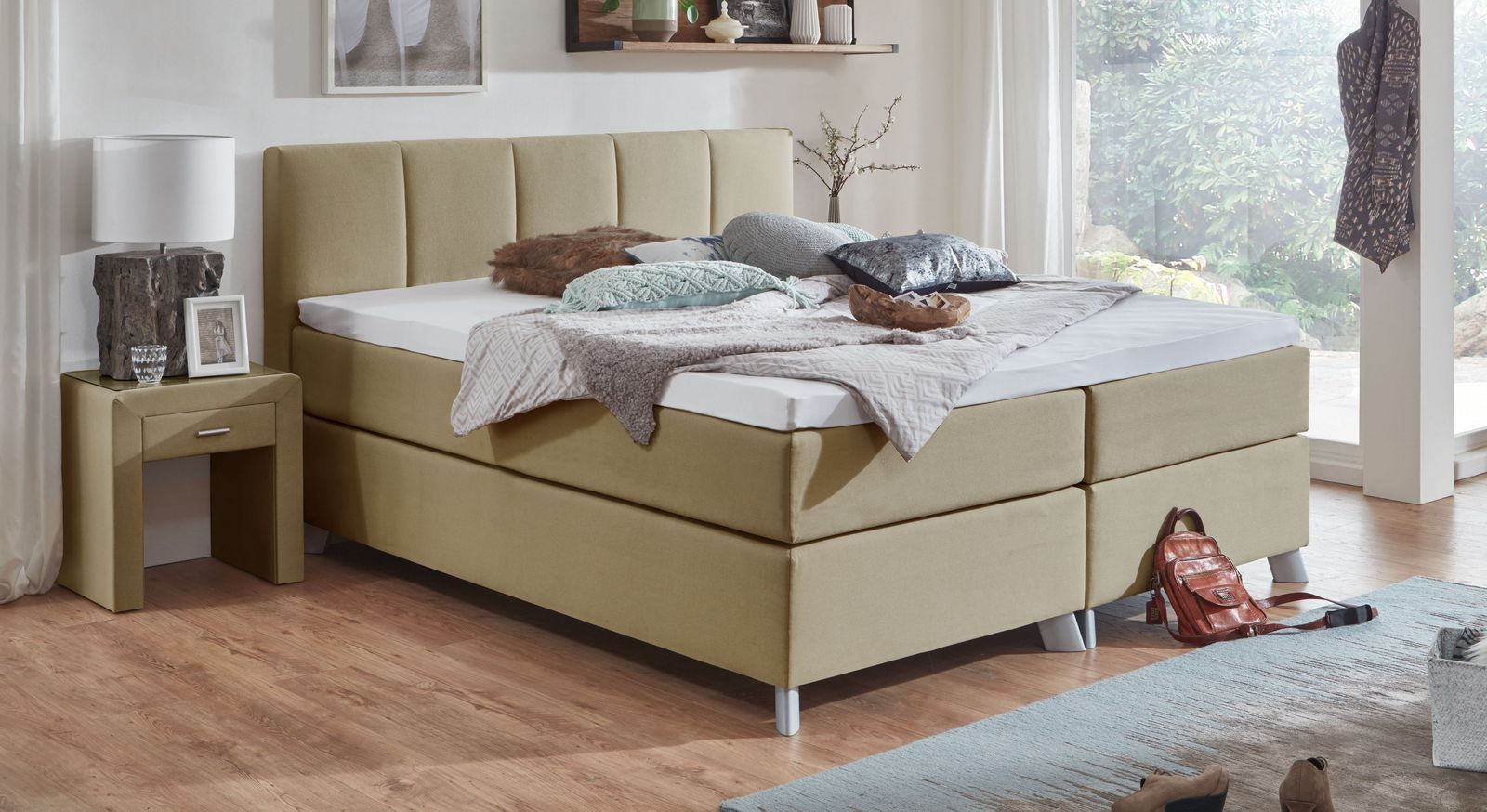 Der naturfarbene Bezug des 66 cm hohen Boxspringbettes "Ramea" passt perfekt in dunkle Räume.
