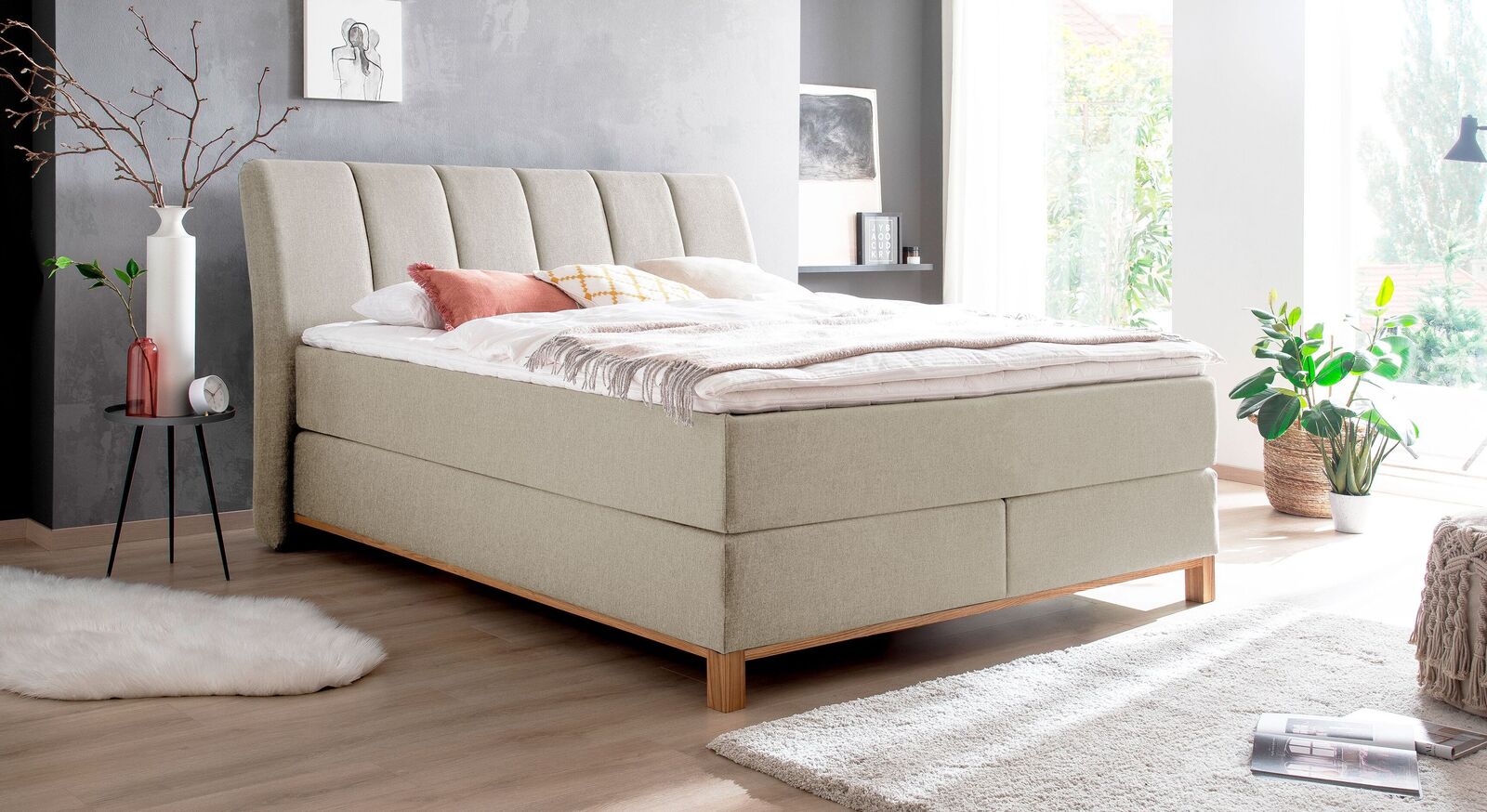 Frisch und modern wirkt das Boxspringbett "Rivelino" mit beigefarbenem Webstoffbezug.