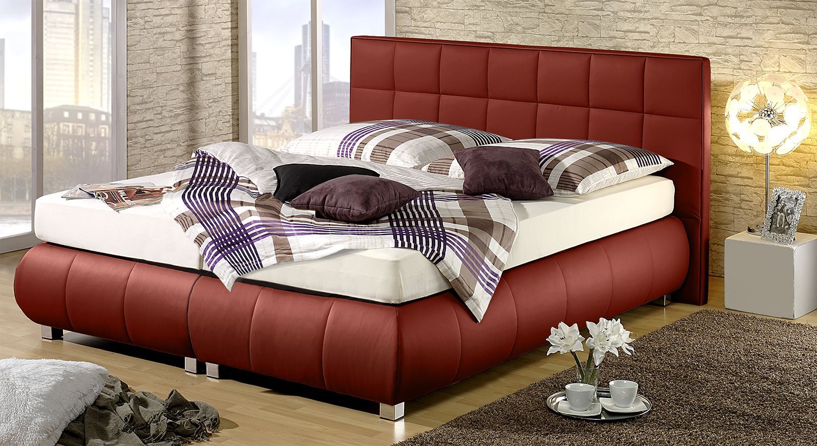 Das rote Boxspringbett überzeugt durch schöne Steppungen.