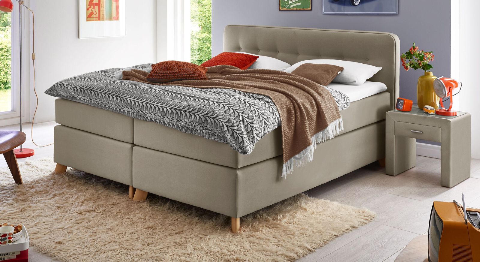 Das elegante Boxspringbett "Summerford" als Ausführung in Komforthöhe mit taupefarbenem Stoffgewand.