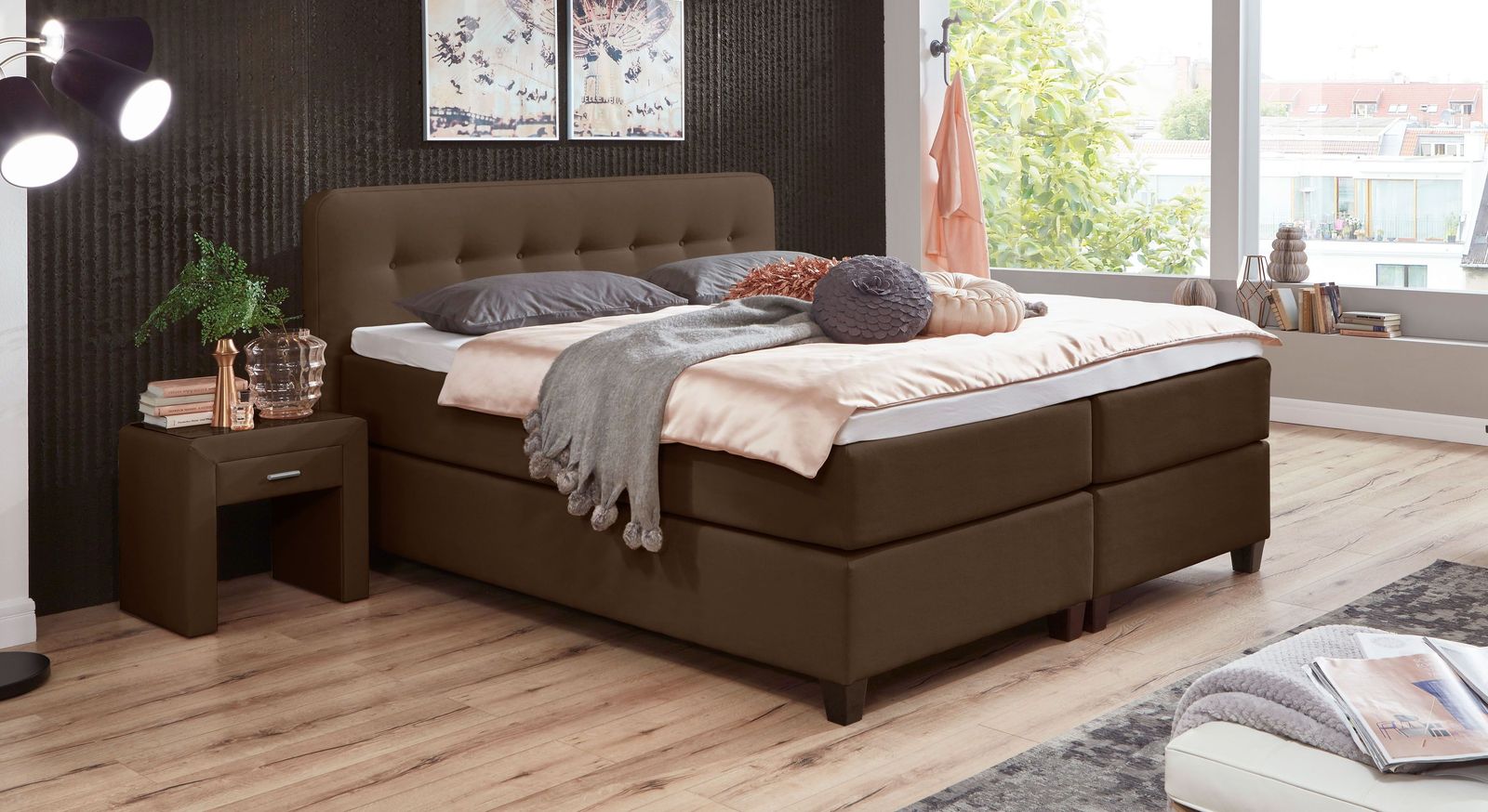 Im braunen Webstoffgewand präsentiert sich das hohe Boxspringbett besonders stilvoll.