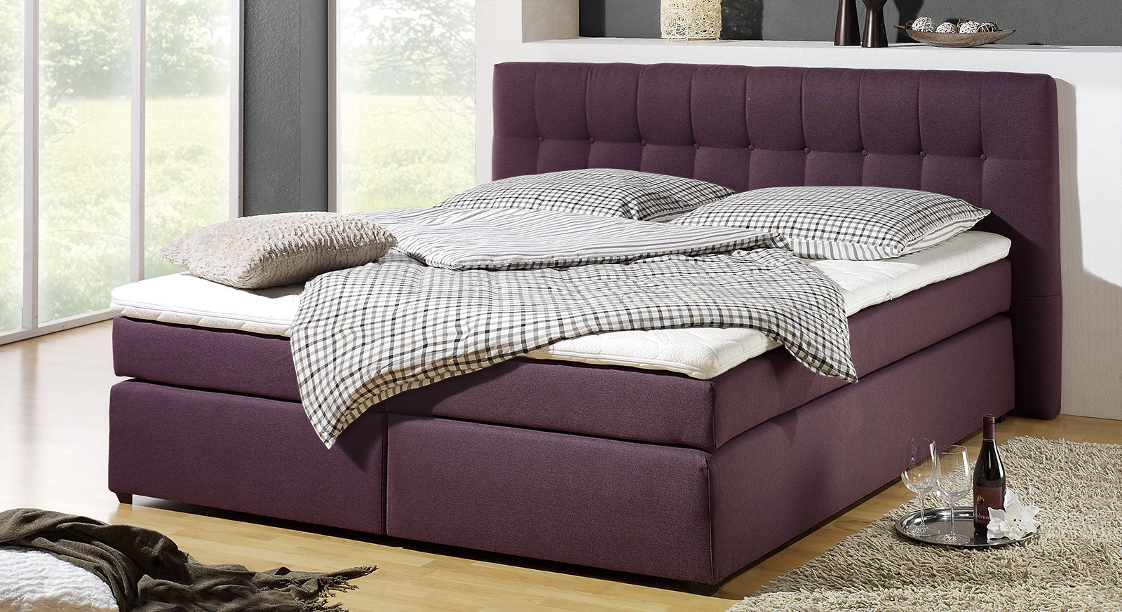 Wer es farbig liebt, für den ist das Boxspringbett "Chicago" mit Stoffbezug im Farbton Beere genau richtig.