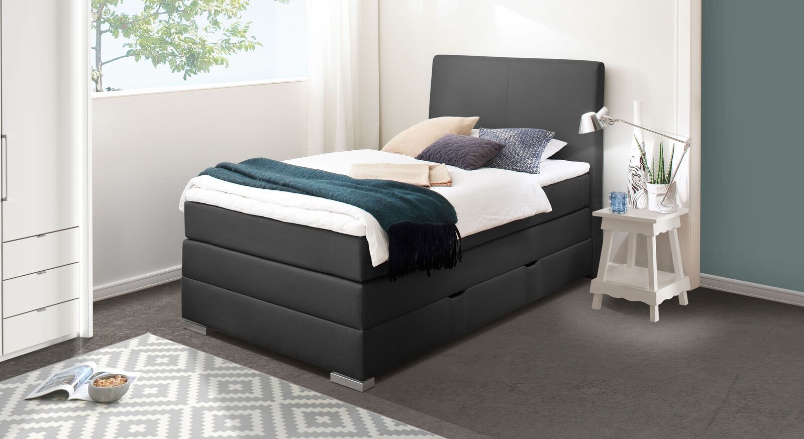Das Single-Boxspringbett "Ivetta" mit ger&auml;umigem Bettkasten und flexibler Ausstattung (hier in anthrazitfarbenem Webstoff mit Metallf&uuml;&szlig;en).