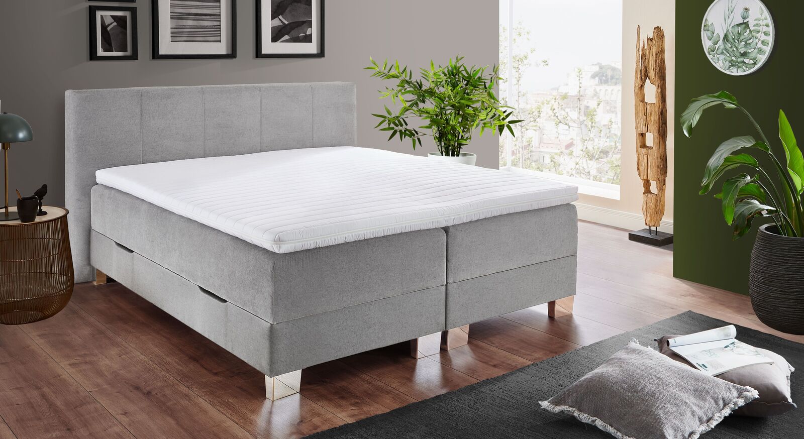 Das Bettkasten-Boxspringbett "Kenan" in hellgrauem Webstoff mit gro&szlig;z&uuml;gigem Stauraum wird inklusive Topper geliefert.