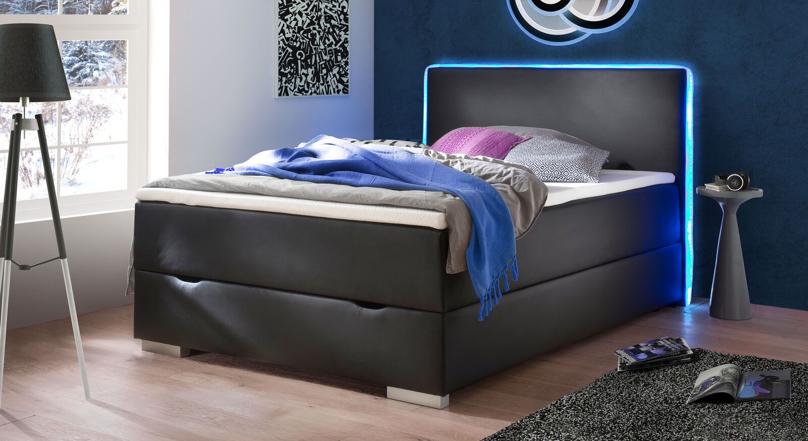 Das Bettkasten-Boxspringbett "Merwin" (hier in 140x200 cm) begeistert mit seinem schwarzen Kunstlederbezug und einem Farbwechsel-LED-Stripe.