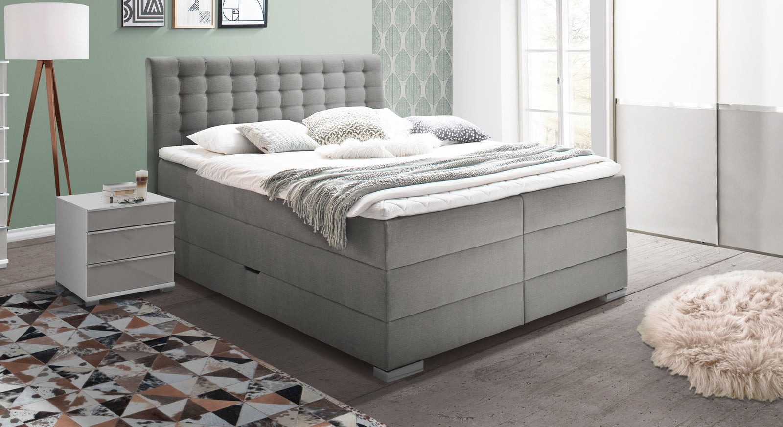 Das Bettkasten-Boxspringbett "Viviana" mit 70 cm Liegeh&ouml;he &ndash; hier im feinen hellgrauen Webstoffbezug mit F&uuml;&szlig;en aus Metall.