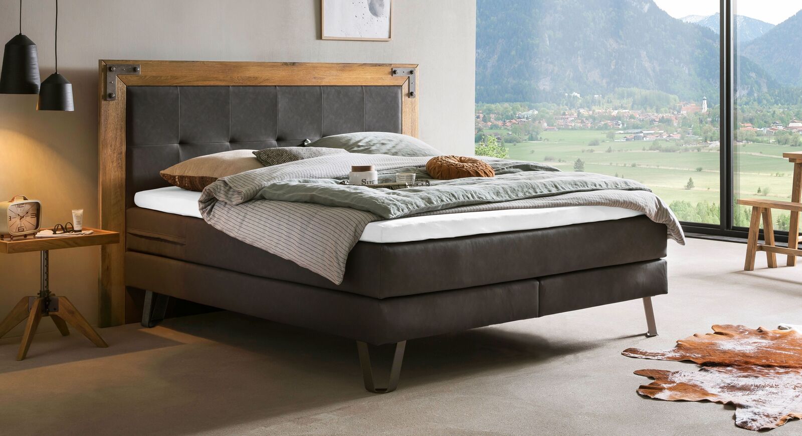 Rustikaler Industrial Style: das Boxspringbett "Arnberg" aus massiver Wildeiche und Kunstleder (hier grau meliert).