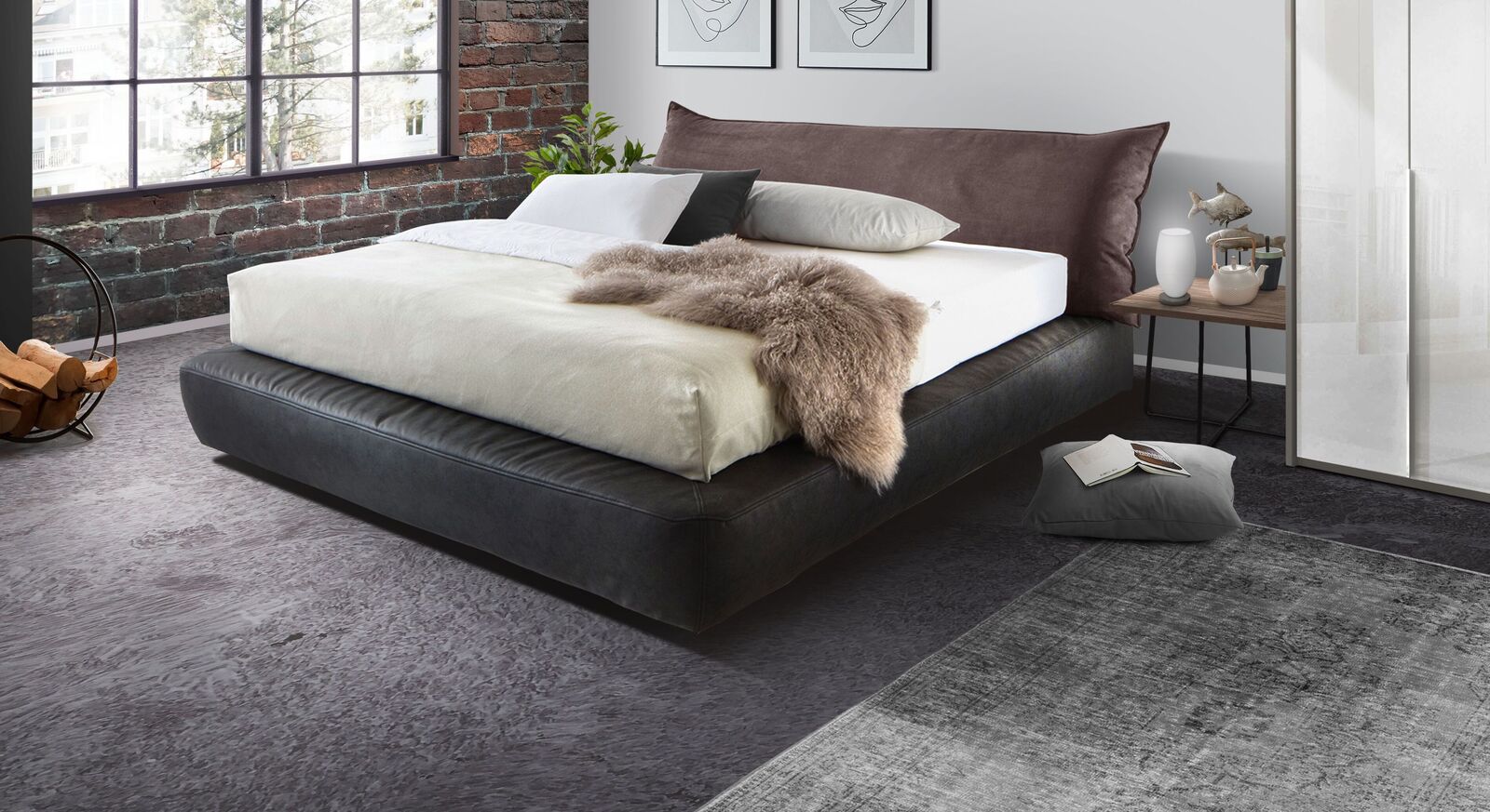 Das Boxspringbett "Benice" (Matratzen-Husse nicht enthalten) mit anthrazitfarbenem Kunstleder und braunen Polster-Kopfteil in gem&uuml;tlicher Kissenoptik.