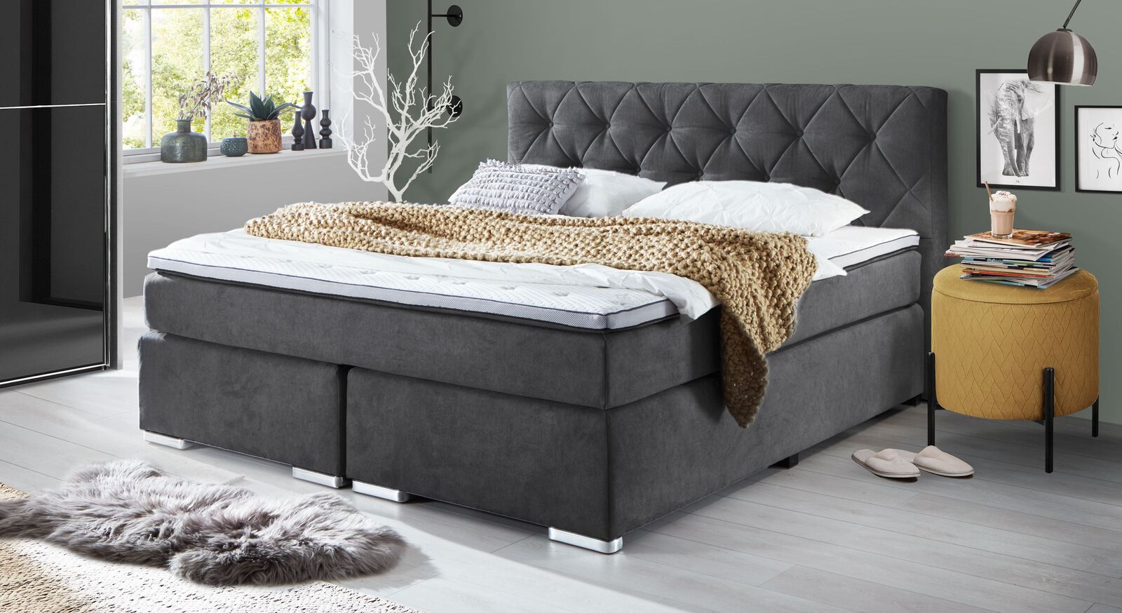 Das markante Retro-Boxspringbett "Bryce" mit grauem Webstoffbezug und aufwendig gestaltetem Kopfteil.