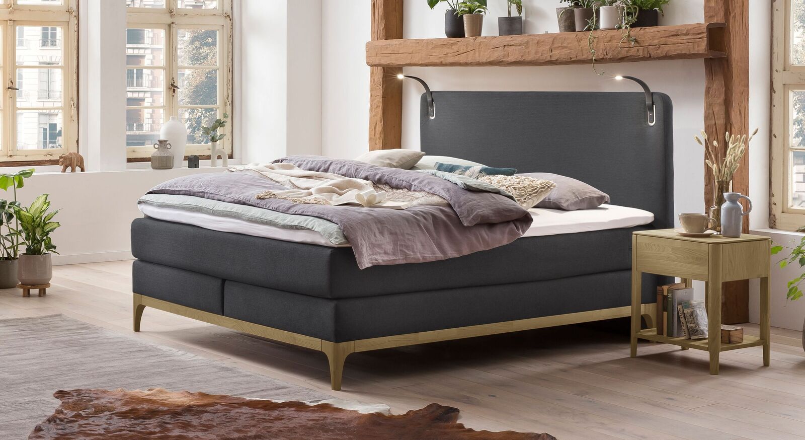 Das komfortable Boxspringbett "Danilo" mit Holzsockel aus massiver Eiche und klassischem Fischgr&auml;t-Velours-Bezug (hier in Anthrazit).