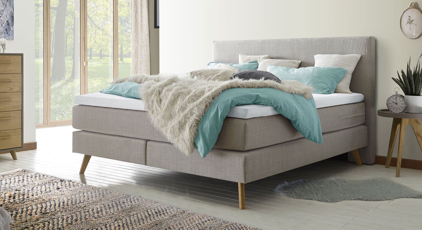 Schaffen Sie sich einen gem&uuml;tlichen R&uuml;ckzugsort mit dem Boxspringbett "Esra" (hier in Hellgrau) mit weichem Webstoffbezug.