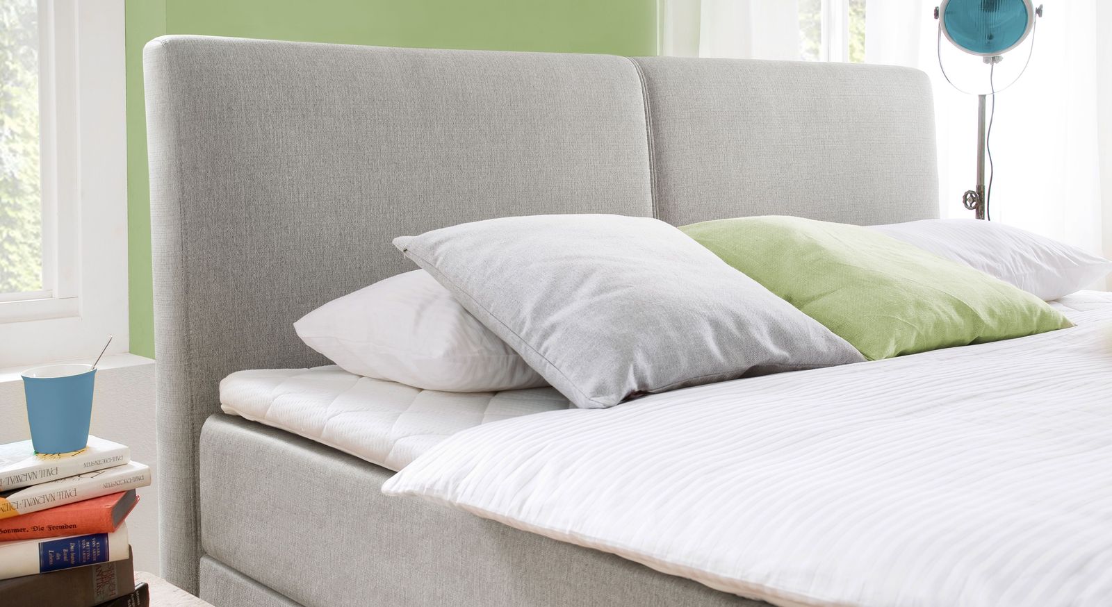 Das gepolsterte Kopfteil des Boxspringbettes "Jaramillo" ist mit einem eleganten Webstoff bezogen und in der Mitte geteilt.
