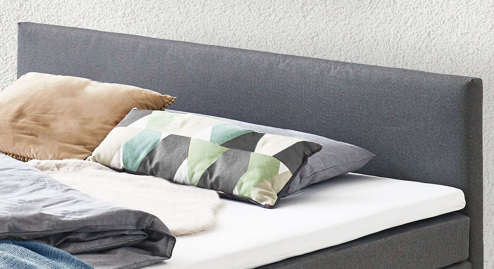Das schlichte Kopfteil ist gepolstert und passt perfekt in das zeitlose Design des Boxspringbettes.