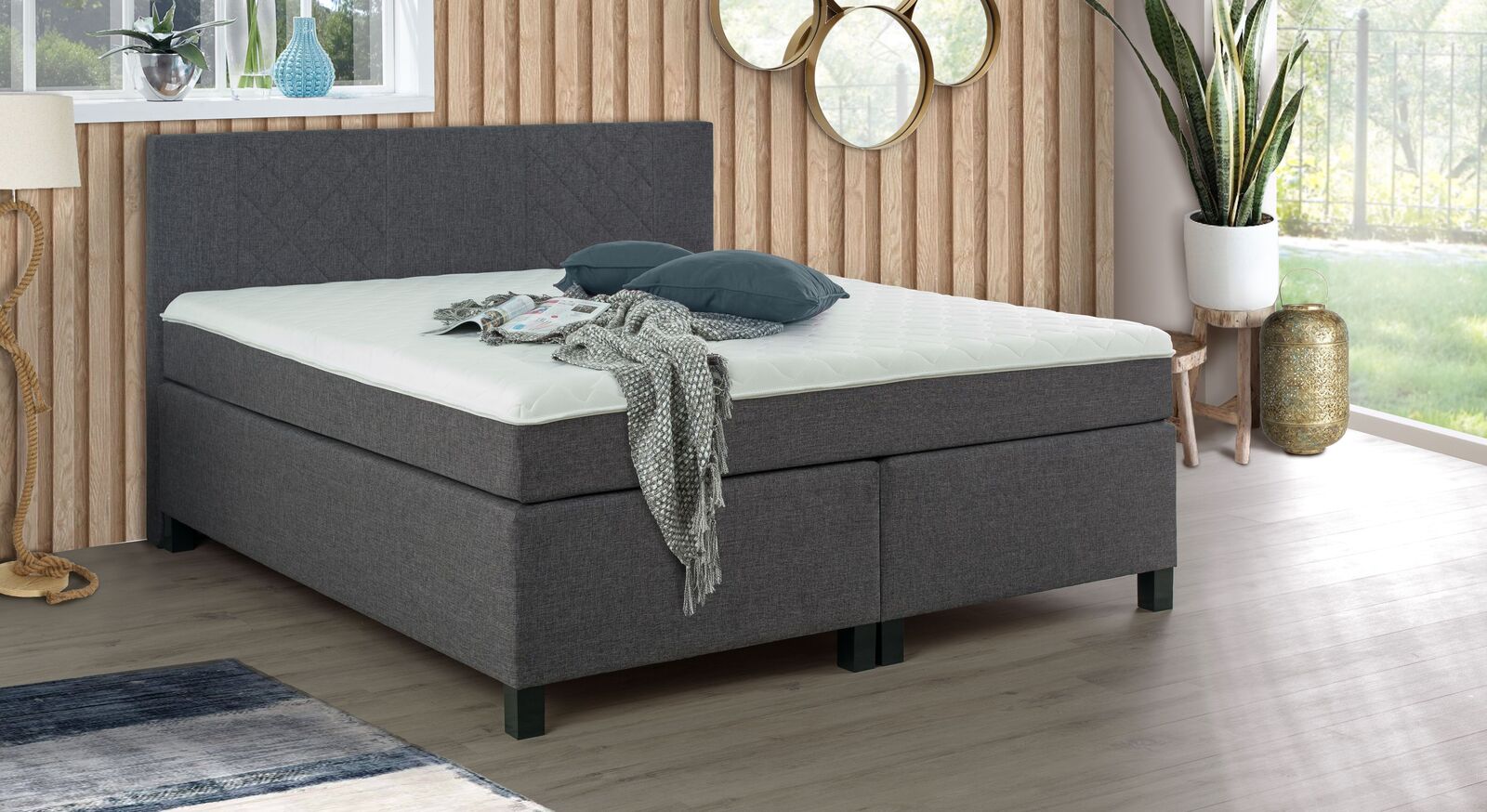 Das anthrazitfarbene Boxspringbett "Ordan" begeistert mit seiner zierlichen Rautensteppung am Kopfteil.