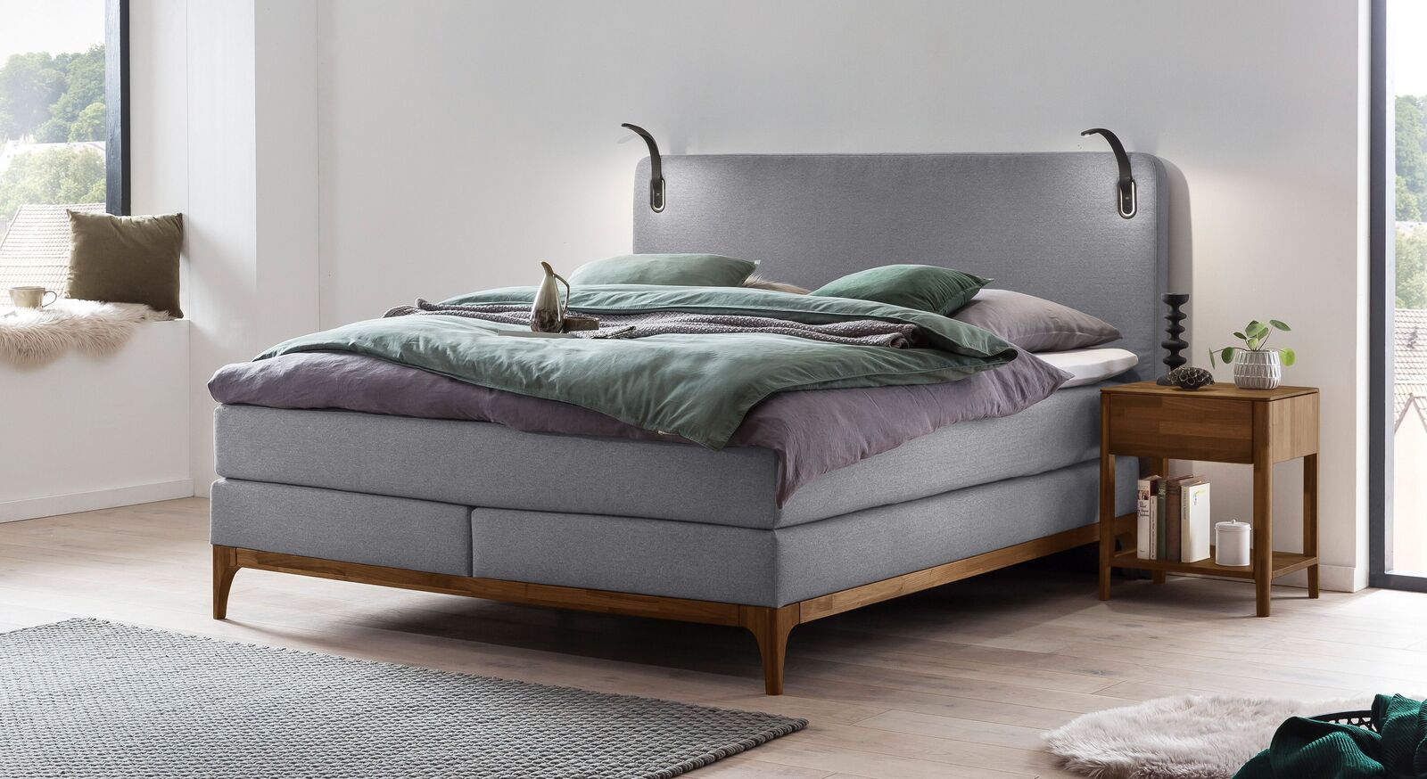 Das elegante Boxspringbett "Palmiro" (hier mit wei&szlig;grauem Bezug) inklusive Leselampen kann individuell an Ihre Bed&uuml;rfnisse angepasst werden.