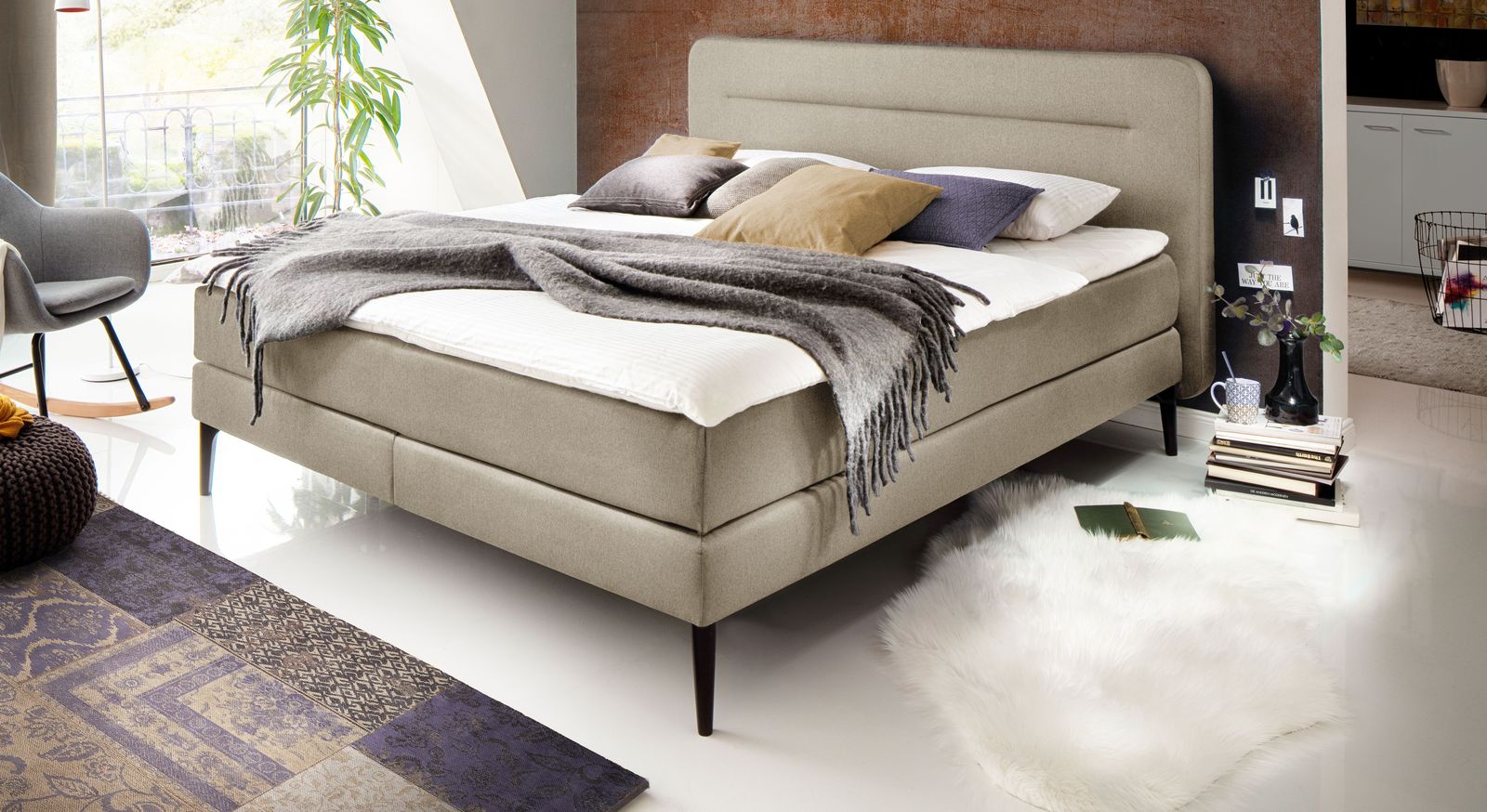 Das moderne Boxspringbett "Paroldo" mit stilvollem Designer-Kopfteil &ndash; hier in Beige mit schwarzen F&uuml;&szlig;en und ohne Unterleisten.