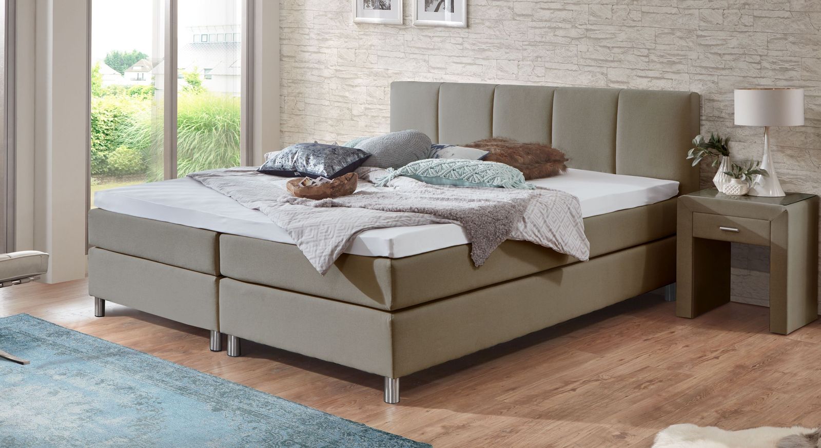 Der Webstoff in Taupe passt perfekt zu den geb&uuml;rsteten Aluminiumf&uuml;&szlig;en des Bettes (Liegeh&ouml;he: 53 cm).