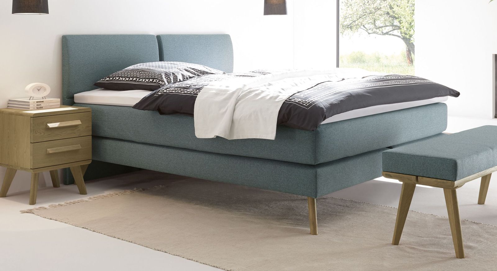 Das luftig leichte Boxspringbett "Viane" im 60er-Jahre-Stil mit weichem Fischgr&auml;t-Velours (hier in Blaugrau).