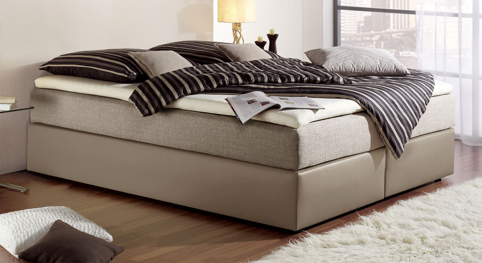 Elegante Boxspringliege "Sydney" &ndash; hier in taupefarbenem Kunstleder und graubeigem Stoff.