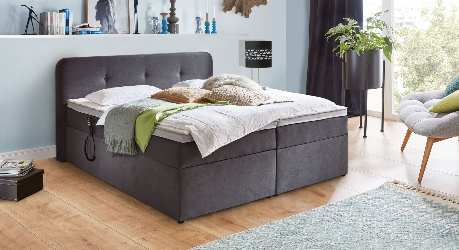Funktional und &uuml;beraus gem&uuml;tlich: Das graue Elektro-Boxbett "Paden" wird inklusive Matratze und Topper geliefert.