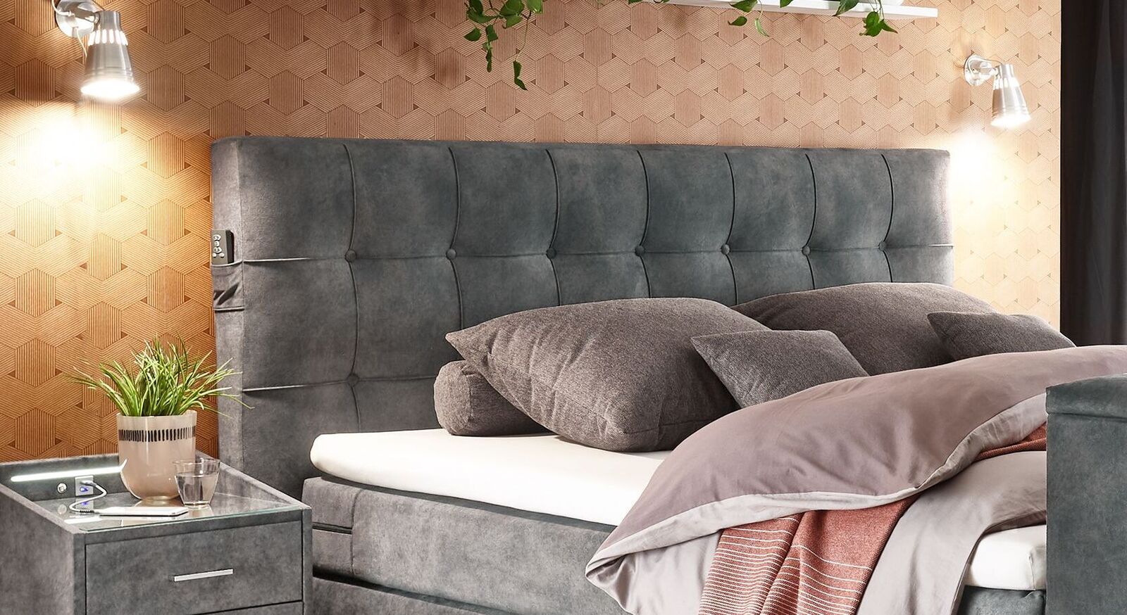 Das gepolsterte Kopfteil ist mit einem anthrazitfarbenen Microvelours-Bezug und einer eleganten Karosteppung versehen.